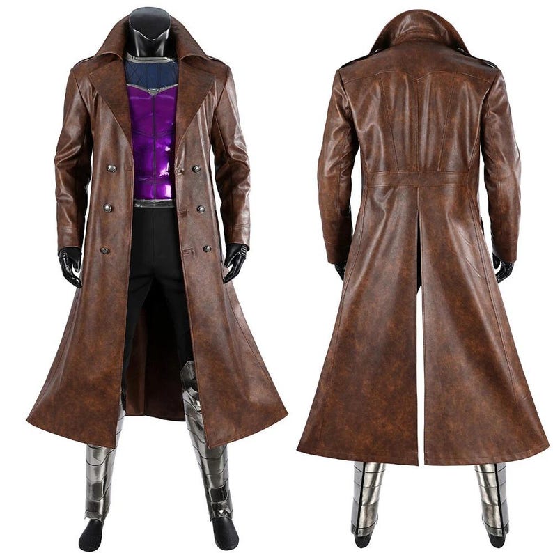 May include: A long brown trench coat with a double-breasted front, wide lapels, and a back vent. The coat is worn over a purple and dark blue top, black trousers, and metallic silver leg guards. The brown material has a textured, weathered finish.