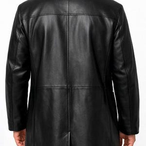 May include: A black leather coat with a classic design. The coat features a notched collar, a button closure, and a long length. The back of the coat has a center vent and vertical seams for a tailored fit. The coat is made of a smooth, shiny leather.