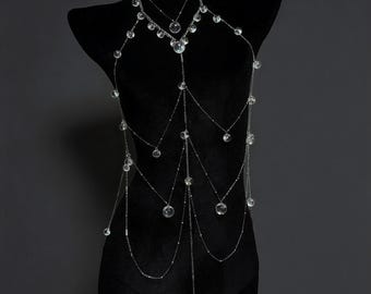 May include: A silver-toned body chain featuring multiple delicate metal strands draped in a layered design. The jewellery is accented with numerous clear, spherical glass beads spaced evenly along the chains, creating a cascading, multi-tiered effect.