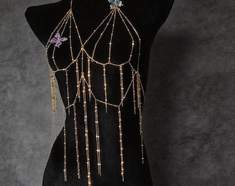 May include: A gold-toned body chain featuring a halter-style neckline and multiple dangling chain strands. The piece is accented with two iridescent butterfly charms, one positioned on each side of the chest area, creating a layered effect.