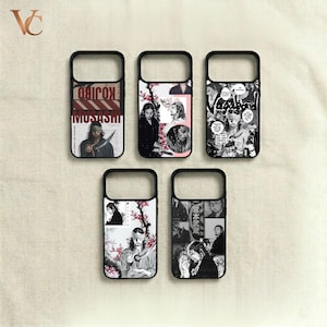 May include: Five black phone cases with unique designs. The cases feature illustrations and text, including the words "KOJIRO MUSASHI" and "Vagabond." The designs incorporate images of a person with long hair, cherry blossoms, and manga-style panels. The cases are displayed on a cream-colored surface.