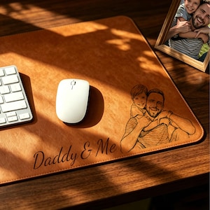 May include: A brown leather desk mat with a personalized image of a father and child, a white computer mouse, and the words "Daddy & Me." A framed photo of the same pair is on the right.