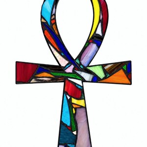 May include: A stained glass ankh symbol featuring a mosaic of multicolored glass shards in shades of red, blue, yellow, green, and purple, all held together by dark metal solder lines, forming the classic Egyptian cross shape against a white background.