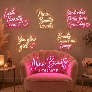 May include: A pink velvet armchair is centered in a room, with several neon signs above it. The signs read "Lush Beauty Lounge", "Nina Beauty Lounge", "Good vibes Pretty faces Great day", "You glow girl", and "Beauty begins in the Lounge".