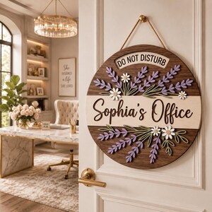 May include: A round wooden door sign featuring a dark brown finish with a light wood center stripe. The sign displays the text "DO NOT DISTURB" and "Sophia's Office" in black script, decorated with layered purple lavender sprigs and white daisies.