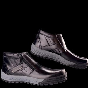 May include: Two black leather ankle boots with gray soles are displayed against a black background. One boot has a zipper closure, while the other has a smooth upper. Both boots have a stitched design on the upper.