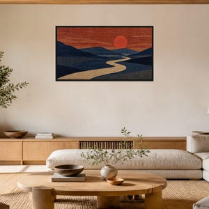 May include: A rectangular wall art piece featuring a landscape with a winding beige river flowing through dark blue hills under a deep red sky with a large, solid red sun. The artwork is enclosed in a thin black frame and mounted on a wall.