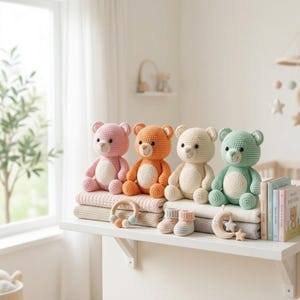 Könnte beinhalten: Vier gehäkelte Teddybären in Rosa, Orange, Creme und Mintgrün sitzen auf einem Regal mit Decken. Ein Beißring aus Holz, Babyschuhe und eine Mond- und Sternendekoration sind ebenfalls ausgestellt. Die Kinderzimmerdekoration ist weich und einladend.