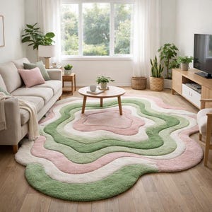 May include: A large, soft area rug with a unique, flowing design. The rug features layers of color, including light pink, white, and various shades of green. The rug is placed in a living room setting with a sofa, coffee table, and plants.