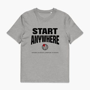Könnte beinhalten: Ein graumeliertes Kurzarm-T-Shirt mit dem schwarzen Schriftzug START ANYWHERE in fetter Schrift. Unter dem Text befindet sich ein schwarzes Liniengrafik-Globus-Symbol mit einer roten Standortnadel und dem Text LATITUDE: XX.XXXXXX | LONGITUDE: XX.XXXXXX.