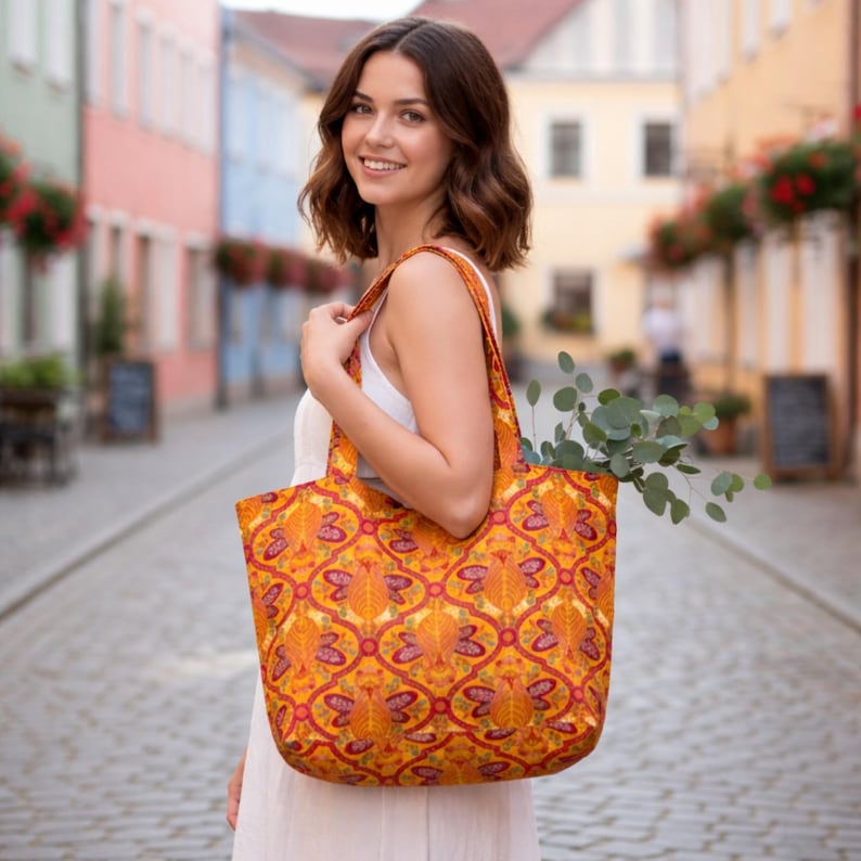 May include: A large tote bag with a vibrant orange and red floral pattern. The bag is carried over the shoulder and filled with greenery. The bag's design features a repeating pattern of stylized leaves and floral elements.