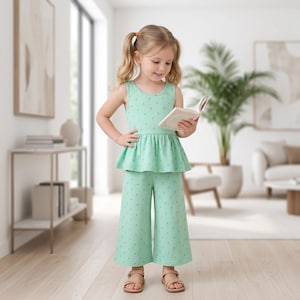 Op de afbeelding: Een mintgroene mouwloze peplumtop en bijpassende wijde, kuitbroek met een klein herhalend gouden sterrenpatroon. De outfit wordt gecombineerd met eenvoudige lichtbruine sandalen voor een geco&ouml;rdineerde uitstraling.