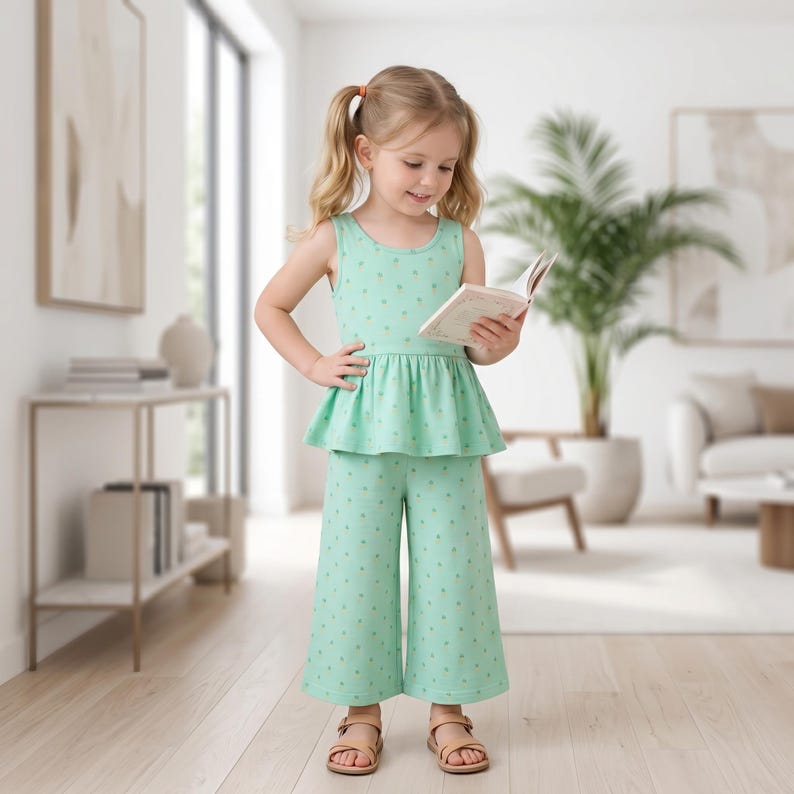 Op de afbeelding: Een mintgroene mouwloze peplumtop en bijpassende wijde, kuitbroek met een klein herhalend gouden sterrenpatroon. De outfit wordt gecombineerd met eenvoudige lichtbruine sandalen voor een geco&ouml;rdineerde uitstraling.