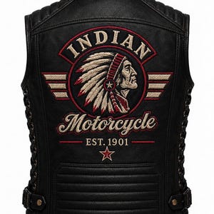 Op de afbeelding: Een zwart leren vest met een grote geborduurde patch op de achterkant met de tekst Indian Motorcycle Est. 1901. Het ontwerp bevat een profiel van een persoon met een verentooi, rode accenten en een ster. Het vest heeft vetersluiting aan de zijkanten.