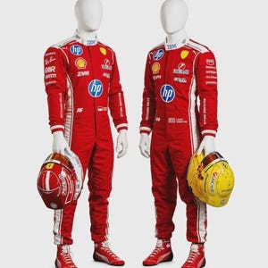 May include: Two red racing suits with white side stripes and various sponsor logos including HP, Shell, and IBM. One mannequin holds a red helmet, the other a yellow helmet. Both wear matching red racing shoes on a plain white background.