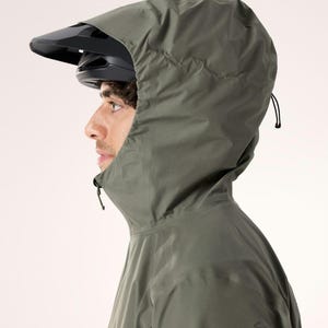 Puede incluir: Una persona con una chaqueta con capucha verde oscuro y un casco de bicicleta negro. La chaqueta tiene un cuello alto y una capucha con cord&oacute;n. Un peque&ntilde;o logotipo es visible en la manga izquierda.