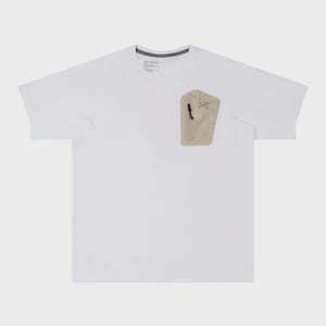 May include: White short-sleeve t-shirt with a beige pocket on the chest. The pocket has a black zipper and a small logo. The shirt has a crew neck and a tag at the neckline.