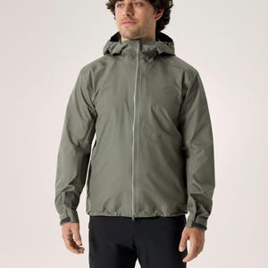 Puede incluir: Chaqueta con capucha verde salvia con cremallera completa, usada con pantalones negros. La chaqueta tiene un dise&ntilde;o aerodin&aacute;mico con capucha y pu&ntilde;os. El modelo est&aacute; de pie frente a un fondo liso.