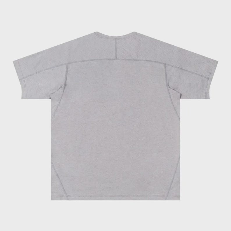May include: A light gray t-shirt with a crew neck and short sleeves. The back of the shirt is visible, showing seams across the shoulders and down the sides. The fabric has a subtle texture.
