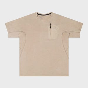 May include: A beige short-sleeved t-shirt with a small pocket on the chest. The pocket has a zipper and a small design. The shirt has a crew neck with a black trim. The fabric appears to be lightweight.