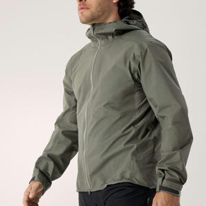Puede incluir: Chaqueta con capucha verde salvia con cremallera completa. La chaqueta tiene un dise&ntilde;o aerodin&aacute;mico con una silueta ajustada y un brillo sutil. Las mangas tienen pu&ntilde;os ajustables. El modelo lleva pantalones deportivos negros.