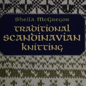 Può includere: Copertina di un libro con il titolo "Traditional Scandinavian Knitting" di Sheila McGregor. Il titolo è in lettere dorate su uno striscione blu navy, su uno sfondo di motivi a maglia bianchi, neri e verdi.