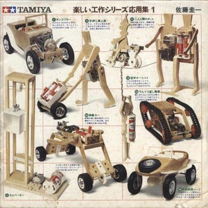 May include: A Tamiya model kit sheet featuring various wooden mechanical models. The models include a car, a robot, a hand-pushed figure, and a tank-like vehicle. The sheet has Japanese text and illustrations.