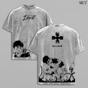 May include: Gray t-shirt featuring manga-style illustrations and text. The front displays a character and the words "in art's Devil". The back has a cross symbol and a kneeling figure. The shirt has a textured appearance.