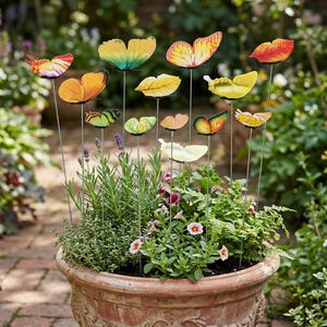 May include: A terracotta flower pot filled with green plants and colorful butterfly garden stakes. The butterflies are various colors, including yellow, orange, and red, and are attached to thin metal rods. The pot is sitting on a brick patio.