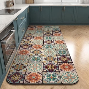 May include: A rectangular kitchen rug with a repeating tile pattern. The tiles feature floral and geometric designs in shades of teal, orange, purple, and yellow. The rug is placed in front of a kitchen counter and cabinets.