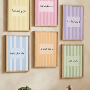 Puede incluir: Seis cuadros rectangulares con marcos de madera clara, cada uno con rayas verticales en amarillo, rosa, morado, azul, naranja o verde. Cada lámina incluye una etiqueta blanca de bordes festoneados con caligrafía árabe negra.