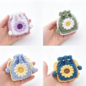 May include: Four handmade crochet drawstring bags in different colors: white with purple flower, green with white flower, light blue with yellow flower, and dark blue with yellow flower. Each bag features a daisy design and a drawstring closure.