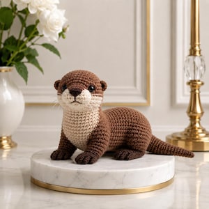 Può includere: Una statuetta di lontra lavorata all'uncinetto a mano con un corpo marrone scuro e un petto e un viso color crema a contrasto. L'animale di peluche ha piccoli occhi neri, un naso marrone scuro e cuciture dettagliate su tutta la superficie.