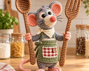 May include: A crocheted gray mouse figurine wearing a cream-colored neckerchief and a green apron with a red and white checkered pocket. The mouse has pink inner ears, a pink nose, and holds a large crocheted brown spoon and a brown fork.