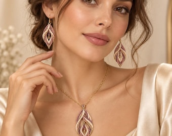 May include: A jewelry set consisting of a necklace and matching drop earrings. Each piece features a leaf-shaped pendant crafted from small, multi-colored beads in shades of cream, mauve, and deep burgundy, suspended on a thin gold-tone chain.