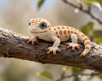 May include: A crocheted gecko figurine featuring a cream-colored body with orange-brown spots, four legs with distinct toes, and large, bright blue eyes. The small stuffed animal is crafted with visible yarn stitches and a textured surface.