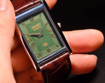 Reloj clásico Seiko Slim Tank vintage con esfera verde y caja plateada.