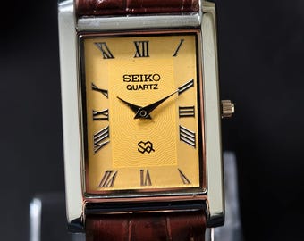 Reloj clásico Seiko Slim Tank vintage con esfera amarilla y caja plateada.
