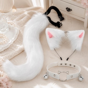 Può includere: Un set cosplay composto da una coda di gatto in finta pelliccia bianca, una fascia per capelli con orecchie di gatto bianche e rosa e un choker bianco con un anello a forma di gatto e campanelli argentati.