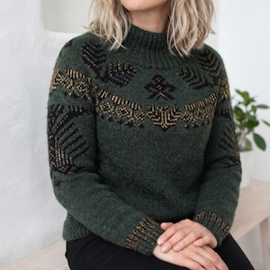 May include: A dark forest green long-sleeve jumper featuring a high ribbed neckline and cuffs. The garment displays a detailed yoke pattern in black and metallic gold thread, incorporating geometric shapes and stylised leaf-like motifs.