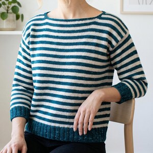 May include: A teal and white striped sweater with a boat neck. The sweater has long sleeves and a ribbed hem and cuffs. The yarn has a speckled texture. The sweater is a casual, comfortable style.