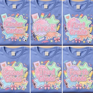 Könnte beinhalten: Ein hellblaues T-Shirt mit einem bunten Grafikdruck von Schulmaterialien wie Notizbüchern, Bleistiften, Sternen und Farbkasten. Der Text lautet Kinder Garten, Pre-K, First Grade, Second Grade, Third Grade und Fourth Grade.