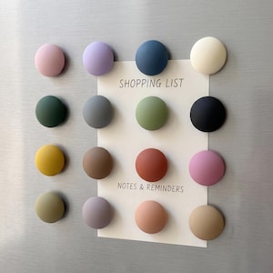 May include: A set of sixteen circular, matte-finish magnets in various colors including pink, purple, blue, cream, green, gray, yellow, brown, terracotta, and black. A rectangular white paper with the text SHOPPING LIST and NOTES & REMINDERS.