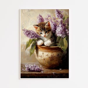 Peut inclure: Une peinture représentant un chaton tigré brun et blanc assis dans un bol en céramique beige orné de motifs floraux bruns. Le chaton est entouré de grappes de fleurs de lilas violettes, avec d'autres fleurs violettes posées sur la surface.