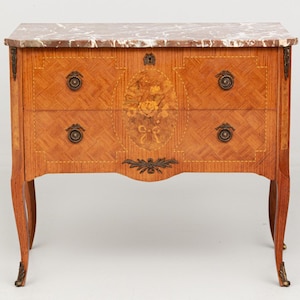 May include: A small, antique wooden chest of drawers with a marble top. The chest features four drawers with ornate brass hardware and a floral inlay. The legs are curved, and the wood has a warm, reddish-brown tone.