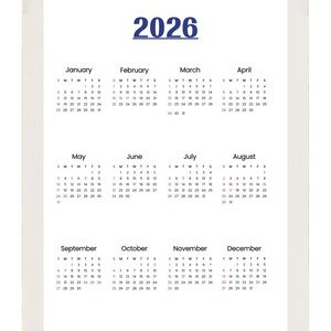 Può includere: Un calendario da scrivania bianco a spirale per l'anno 2026. Il calendario mostra i mesi da gennaio a dicembre, con i giorni e le date di ogni mese chiaramente stampati. L'anno 2026 è stampato in blu.
