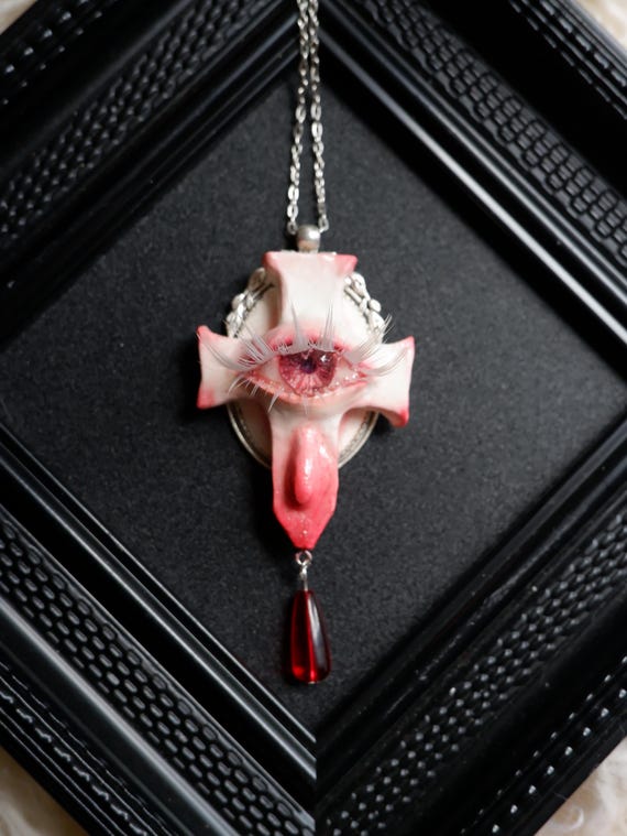Handmade resin cross pendant with a creepy embedded eyeball — exactly the kind of wearable oddity that makes goth and dark-aesthetic collectors do a double-take.