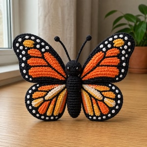 May include: A handcrafted crochet butterfly in vibrant orange, black, white, and yellow. The butterfly features detailed wing patterns and a black body with antennae. This decorative item is likely a home decor piece or a unique gift.