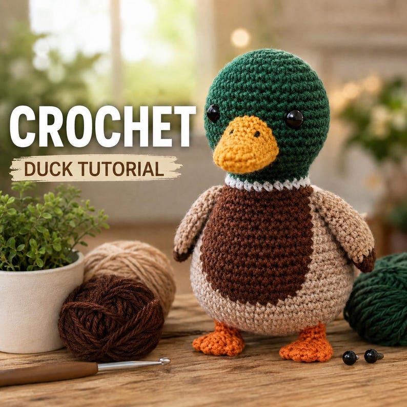 May include: A crocheted mallard duck toy with a dark green head, orange beak, white neck ring, brown chest, and light brown body. The text CROCHET DUCK TUTORIAL is visible. Nearby are yarn balls, a crochet hook, and two small black safety eyes.