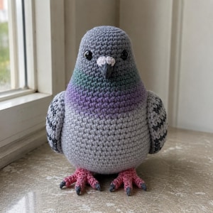 May include: A crocheted pigeon figurine featuring a rounded body with light grey yarn, a purple and green iridescent neck section, dark grey wing markings, black plastic eyes, a small white cere, a dark beak, and textured pink feet.